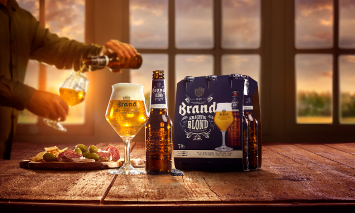 Brand Krachtig Blond  Brand Krachtig Blond sixpack en glas op tafel met hapjes ernaast